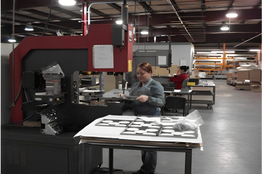Person working with metal sheets in an industrial workshop.